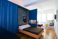 25 a Murphy bed integrated between the living room and the kitchen behind the bold blue doors