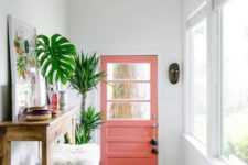 25 summer vibes are achieved with a pink door, a bright boho rug, potted palms and a bold artwork