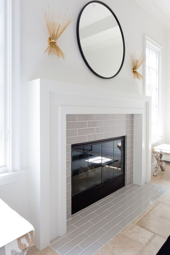 a clean and fresh idea of cladding your fireplace with thin light grey tiles and a white mantel covering the whole piece