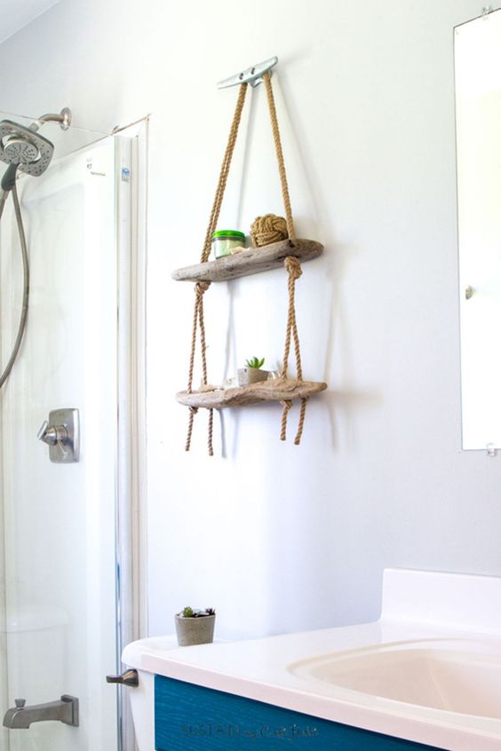 a small hanging display shelf for a bathroom made of driftwood and ropes will add decorative value to the space