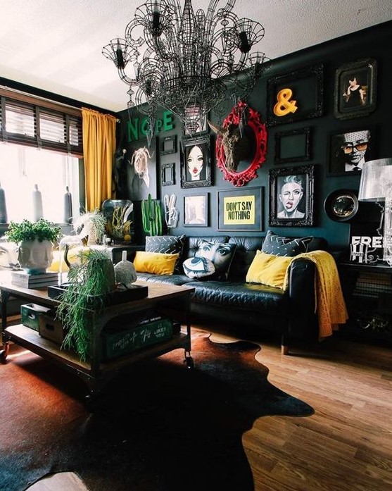A beautiful eclectic living room with a black accent wall and a bold gallery wall, a black sofa and bright pillows, a tiered coffee table and a black chandelier.