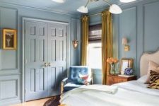 a blue eclectic bedroom with a neutral bed and bedding, a pink bench, a blue chair, gold drapes and a chandelier
