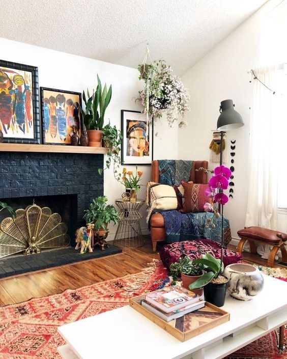 A bright eclectic living room with folksy rugs and blankets, potted greenery and blooms, lamps and bold artworks.