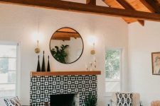 a bright monochromatic mid-century boho living room with a fireplace clad with black and white graphic tiles and a wooden mantel