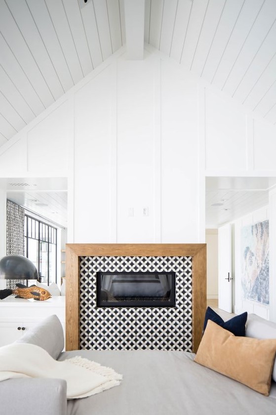 A built in fireplace clad with black and white graphic tiles around and with a wooden frame for a contemporary space