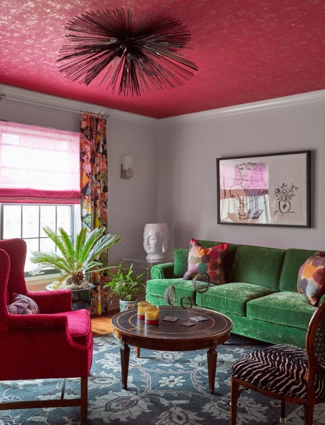 A captivating eclectic living room with a green sofa, pink chair, and pink ceiling. The round table and zebra print chair add unique touches. This mix of vibrant colors and patterns makes for an exciting and stylish space.