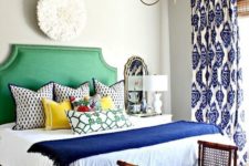 a colorful eclectic bedroom in bold blue and emerald green, with a mix of prints and vintage touches