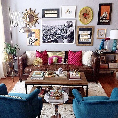 A colorful eclectic living area with a crazy gallery wall, velvet and leather furniture, an industrial coffee table.