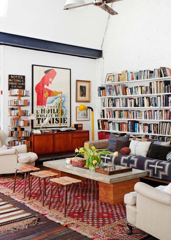 A colorful eclectic living room with open bookshelvesm bright printed textiles, neutral furniture and touches of mid century modern
