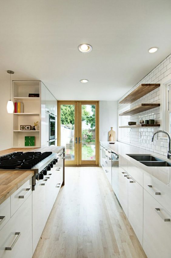 a contemporary neutral galley kitchen with white cabinets and butcher block countertops plus a white subway tile backsplash