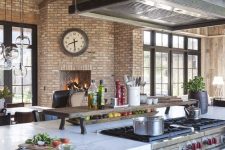 a fantastic eclectic kitchen with brick walls, blue cabinets and metal appliances, pendant lamps and bold decor