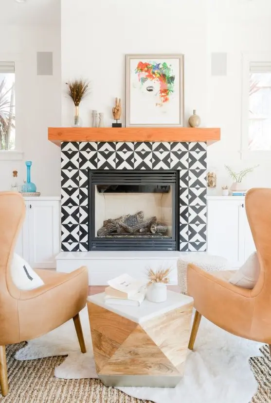 A faux fireplace with black and white graphic tiles clad around and a rich stained wooden mantel