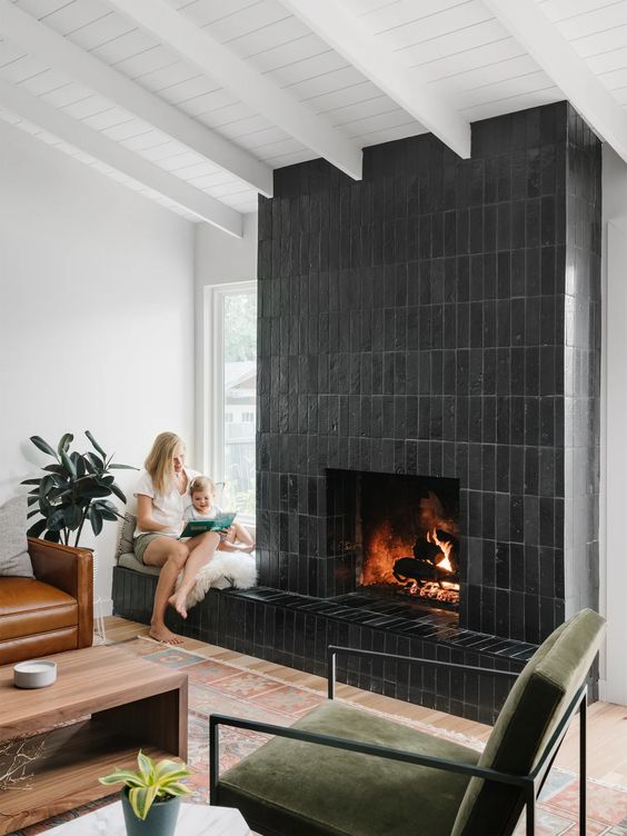 a fireplace clad with black skinny tiles is a lovely solution for a mid-century modern living room, it looks cool and chic
