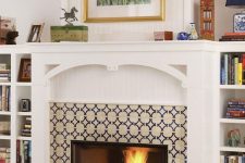 a fireplace surrounded with bright printed tiles, with an elegant mantel and built-in bookshelves on both sides is cool