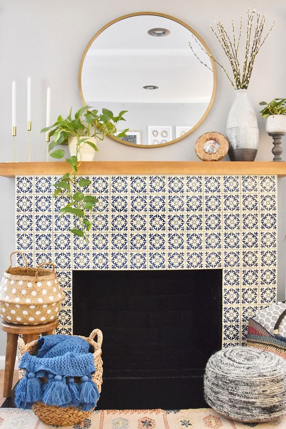 a fireplace surrounded with super chic bright printed tiles, wiht a stained mantel and some decor, baskets with blankets