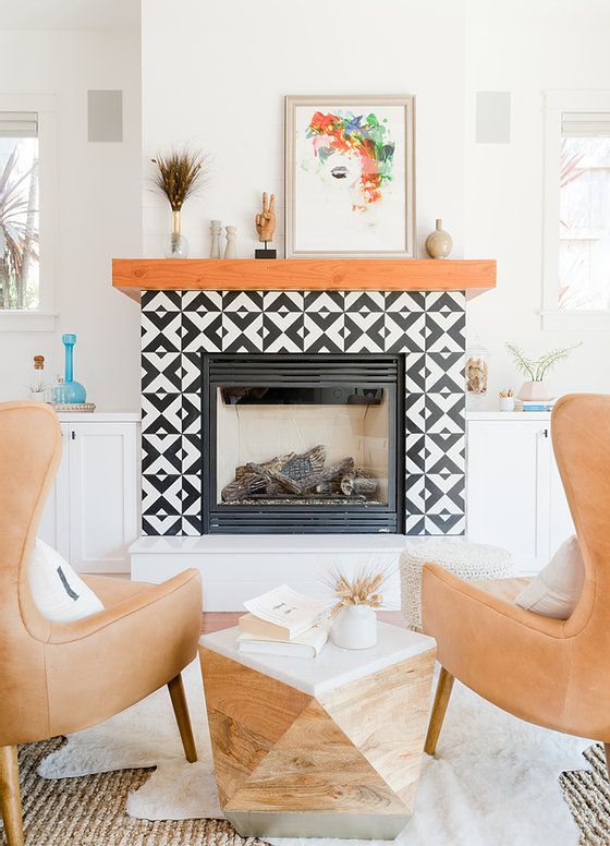 A fireplace with a black and white printed tile surround, a stained mantel, some decor is perfect for a mid century modern living room