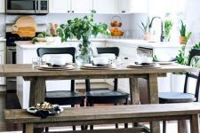 a fresh contemporary kitchen in white with a rustic dining zone with benches and touches of black for drama