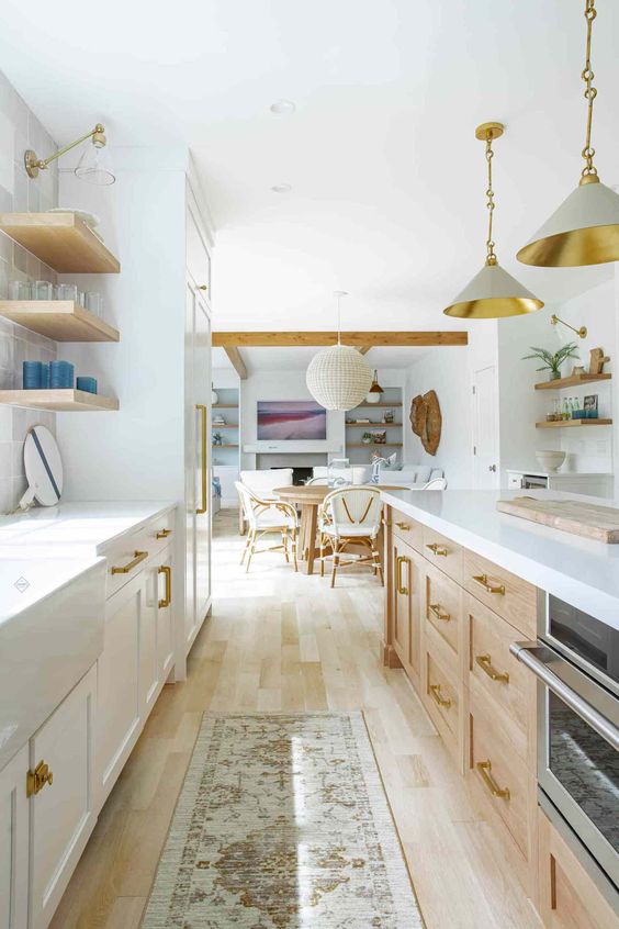 a light-filled farmhouse galley kitchen with white and stained cabinets, open shelves, pendant lamps and white stone countertops