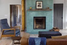 a living room with a stained ceiling, a leather sofa and a fireplace clad with aqua-colored Zellige tiles
