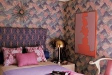 a lovely maximalist bedroom with brushstroke walls, a printed bed, pastel bedding, a pink chair, a gold sculptural chandelier