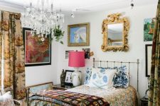 a maximalist guest bedroom with a metal bed, a rattan chair, vintage nightstands, floral textiles and a gallery wall