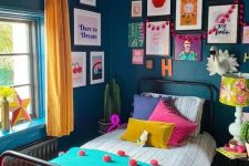 a maximalist guest bedroom with a metal bed, navy walls, a colorful gallery wall, a bright floral lamp and yellow curtains, colorful bedding