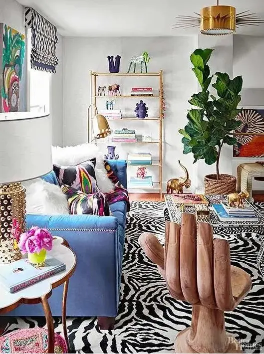 A maximalist living room with a blue sofa, a whimsy chair, colorful rugs and pillows and a bold statement plant in a basket.
