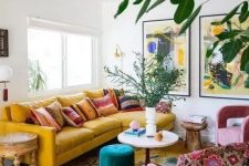 a maximalist living room with a yellow sofa, pink chairs, various tables and bold artworks plus potted plants