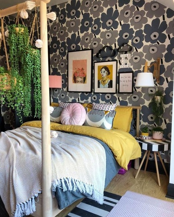 A mid century modern maximalist bedroom with a floral accent wall, a wooden bed with a stand for hanging plants and a striped stool