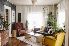 a modern eclectic and boho living room with a black leather sofa, a mustard and burgundy chair, potted greenery and some cool decor