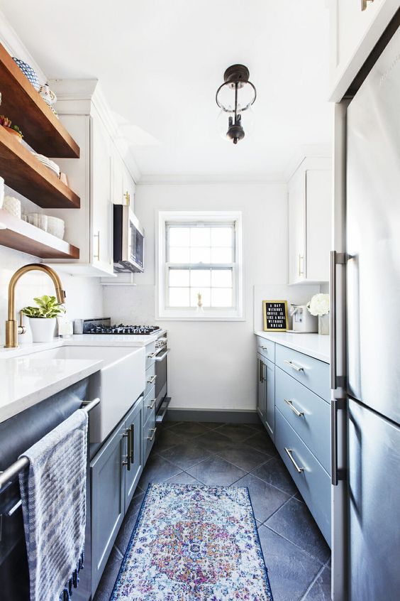 a modern farmhouse galley kitchen in light blue and navy, with white countertops, brass touches and wooden shelves