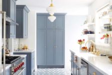a modern farmhouse kitchen in powder blue with a mosaic tile floor, elegant pendant lamps and gilded touches for more elegance