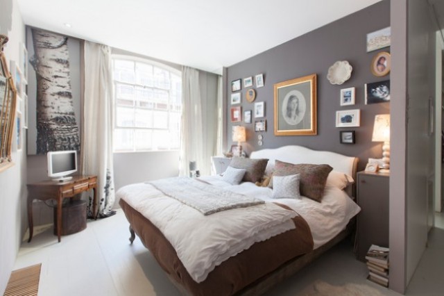A monochrome eclectic bedroom done in grey, white and rich brown, with a vintage inspired gallery wall, a refined bed and table and modern nightstands