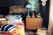 a moody eclectic bedroom with black walls, a bed with bright bedding, a logn shelf with potted plants, bright rugs and some decor