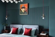 a moody eclectic bedroom with dark green walls and paneling, a dusty blue bed and bold bedding, dark-stained nightstands