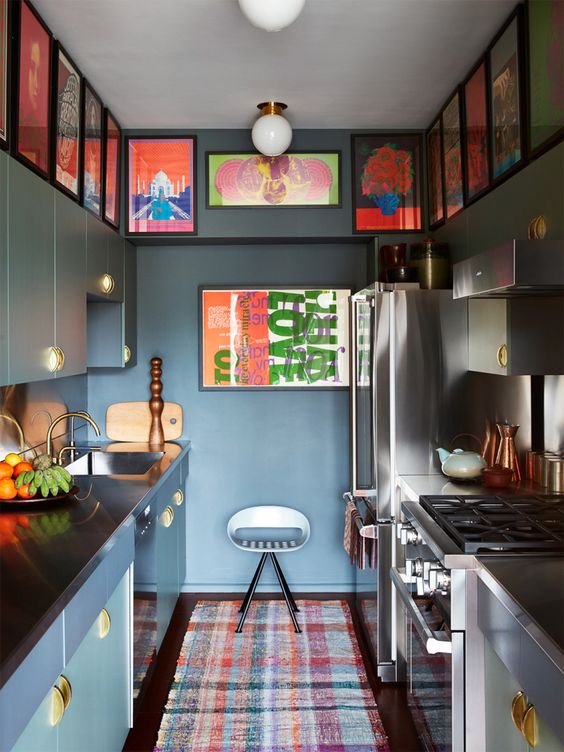 a moody green kitchen with matching cabinets, a gallery wall taking both sides and a bold and bright rug