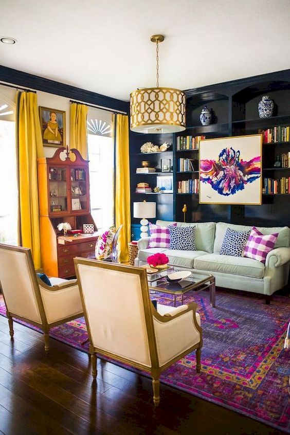 A moody yet bright eclectic living room with dakr walls, yellow curtains, printed pillows and a boho rug plus a vintage buffet.