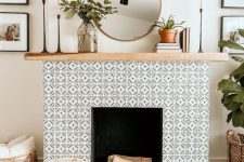 a non-working fireplace with black and white geo tiles clad around and a light stained wooden mantel