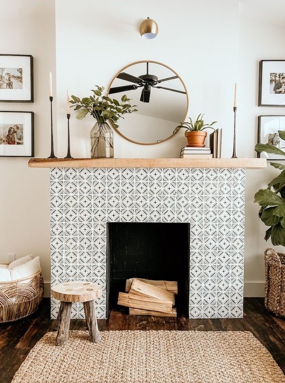 A non working fireplace with black and white geo tiles clad around and a light stained wooden mantel