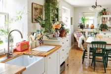 a pretty eclectic kitchen with neutral cabinets, butcherblock countertops, a green storage unit, a dining table with mismatching chairs