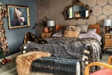 a refined dark maximalist bedroom with black walls and a metallic printed one, a wooden bed and layered bedding, a soft bench with faux fur and a beaded chandelier