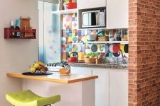 a small eclectic kitchen with white cabinets, grey stone countertops, a small kitchen island, a colorful tile backsplash