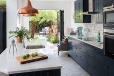 a stylish galley kitchen with navy cabinets and white stone countertops, copper pendant lamps and a brick backsplash