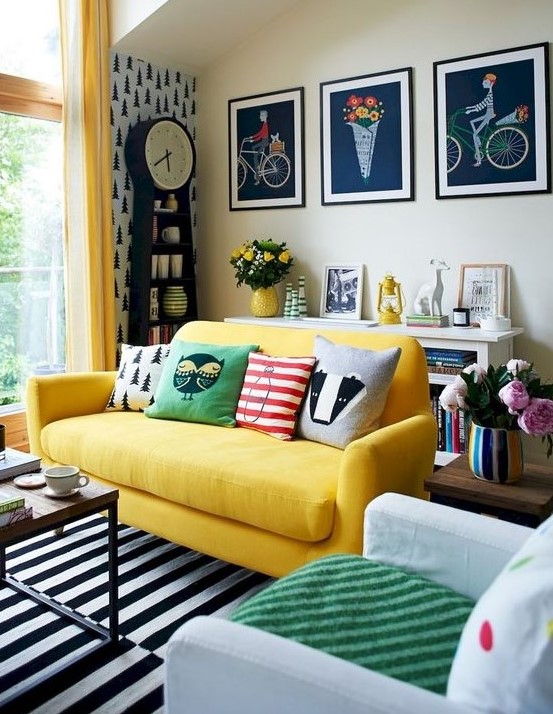 A super colorful eclectic living space with a grid gallery wall, a yellow sofa, lots of prints and a contemporary coffee table.