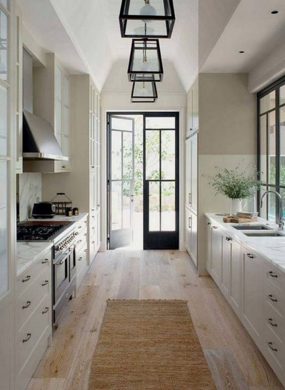 A vintage inspired galley kitchen with white cabinets, white stone countertops and touches of blakc for drama