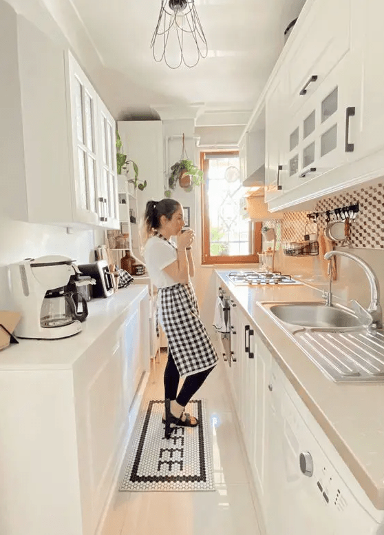 A white galley kitchen with glass cabinets, neutral countertops and backsplashes and some black details for more eye catchiness