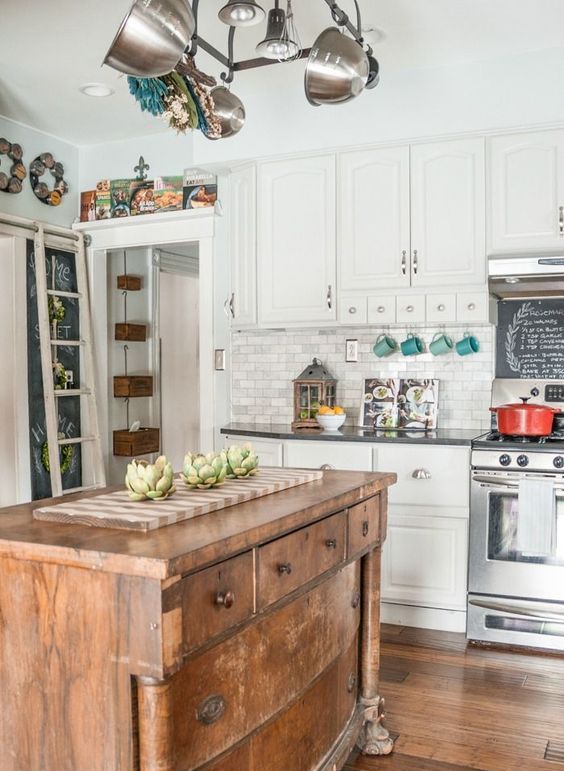 a white traditional kitchen with dark countertops spruced up with a vintage wodoen kitchen island to make it more relaxed