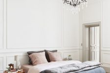 an eclectic bedroom with molding, a bed with pastel bedding, mismatching nightstands, a vintage chandelier