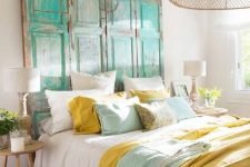 an eclectic bright bedroom with a bed and mustard and aqua bedding, a turquoise shabby chic headboard, matching stools and lamps