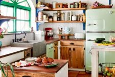 an eclectic kitchen with white and stained cabinets, a light green fridge, open shelves and pendant lamps, some shabby chic furniture